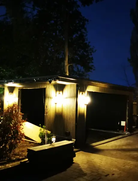 Driveway and garage with exterior lighting at dusk