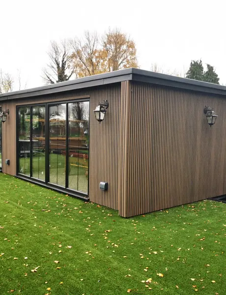 Timber-clad garden room with external wall lights and glazed doors
